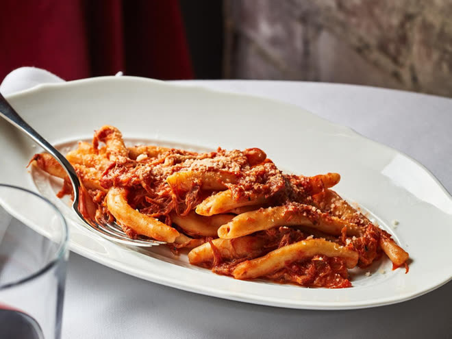 Casarecce pasta in a rich tomato ragù on a white oval plate.