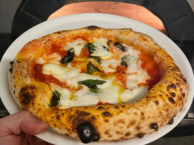 A Neapolitan margherita, blistered at the crust, lifted from the mouth of the oven.