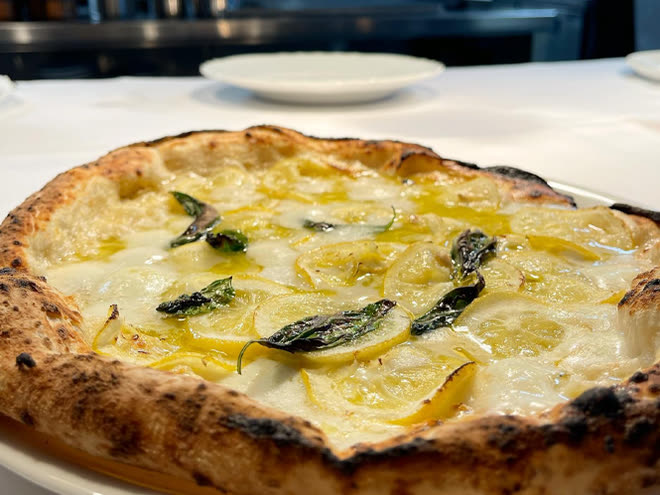 A pizza of thinly sliced potato, mozzarella and basil, fresh from the oven.