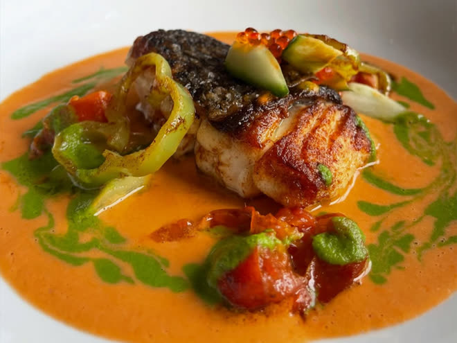 Seared fish on a bright shellfish bisque, dressed with herb oil and courgette flowers.