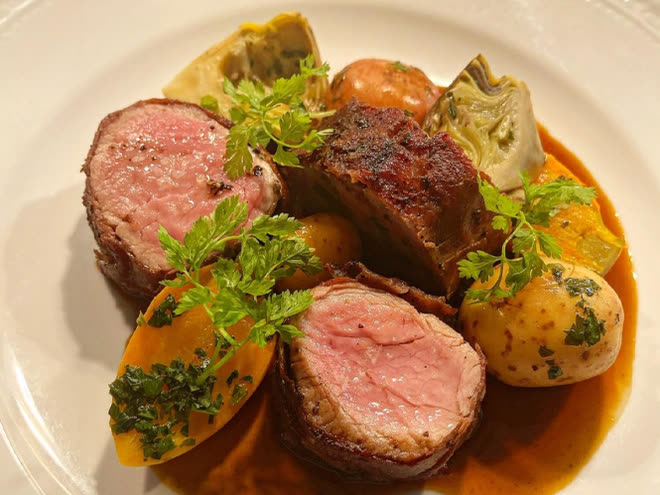 Sliced pork tenderloin with artichokes, new potatoes and herbs in a saffron sauce.