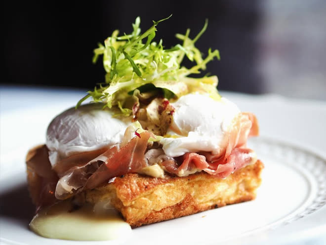 A poached egg and prosciutto over a crisp potato cake, topped with frisée.
