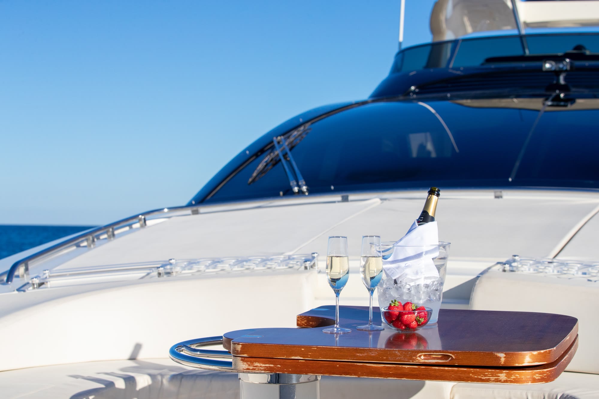 Champagne and strawberries set out on the deck of a yacht at sea.