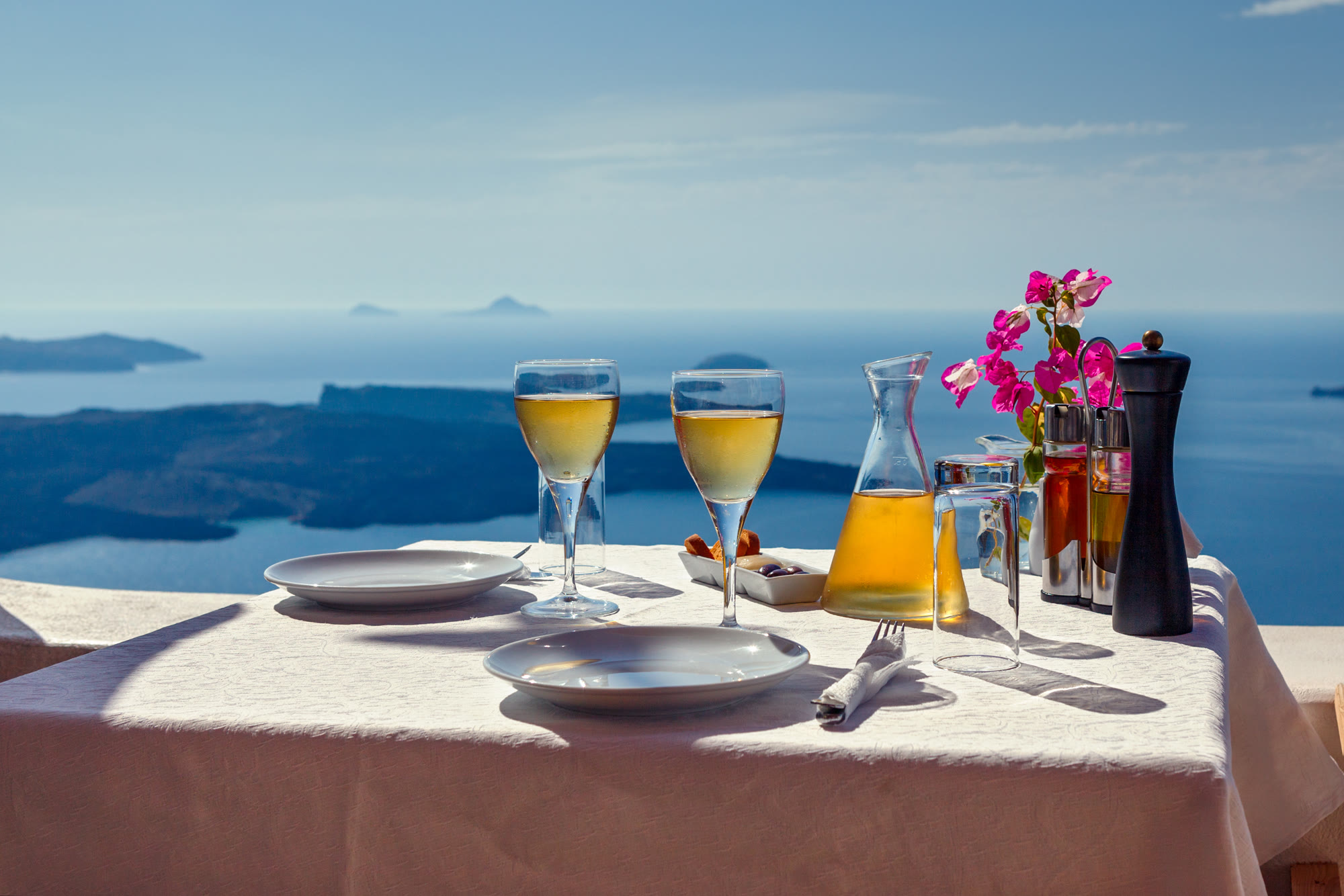 A table with two glasses of wine overlooking the Santorini caldera.